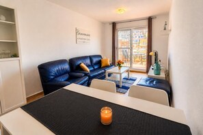 A modern living room with a sofa, a dining table, and a small side table with a candle. - Casa Miramar | Beach, Pool & Terrace in Mojácar Playa (Mojácar)
