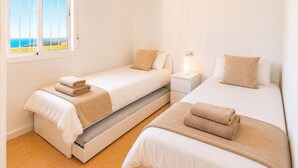 Una habitación de hotel con dos camas, una mesita de noche y un ventanal con vistas.