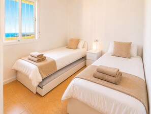 Een hotelkamer met twee bedden, een nachtkastje en een raam met uitzicht.