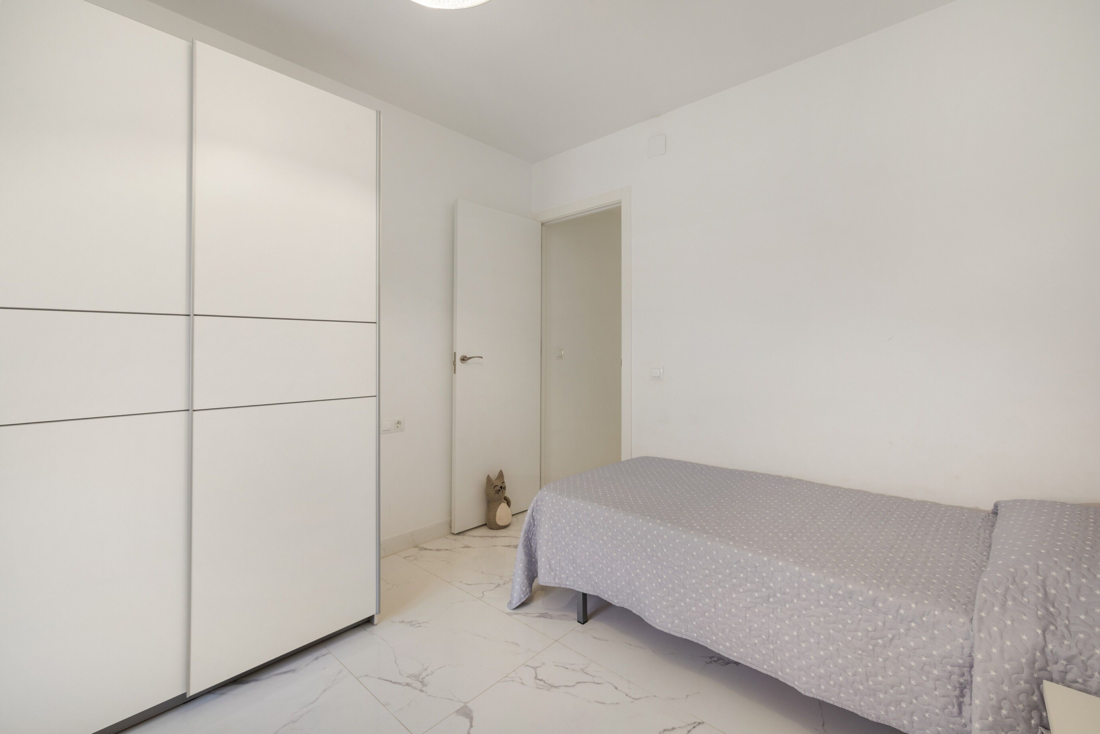 Ein Schlafzimmer mit einem Bett, einem Kleiderschrank und einer Tür zu einem weiteren Raum.
