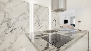 A modern kitchen with a marble backsplash, a built-in stove, and a sleek countertop.