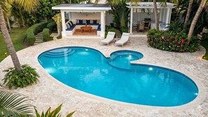 A swimming pool with a sunken seating area, surrounded by palm trees and a patio with a grill. - Spacious 2 bedroom apartment + sofa bed | Swimming pool | Near Bávaro Beach (Punta Cana)