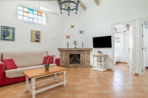 Ein Wohnzimmer mit Kamin, einer Couch, einem Couchtisch und einem an der Wand befestigten Fernseher.
