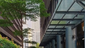 A pathway leading to a modern building with a glass entrance, surrounded by greenery and a paved area. - Summer Suites KLCC by CozyNest (Kuala Lumpur)