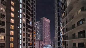 A nighttime view of high-rise buildings with illuminated windows and a central courtyard with a water feature. - Summer Suites KLCC by CozyNest (Kuala Lumpur)