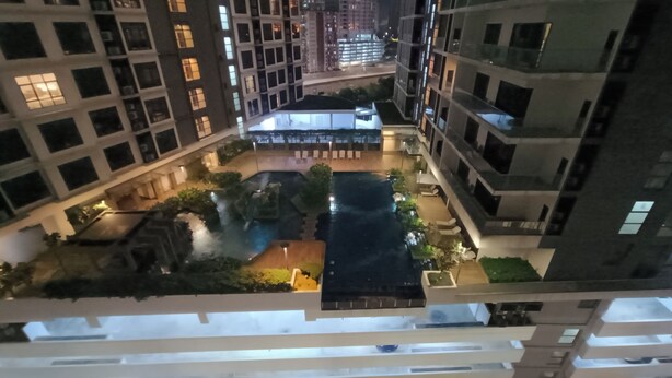 A high-rise residential building with multiple balconies, a central courtyard with a pool, and surrounding greenery. - Summer Suites KLCC by CozyNest (Kuala Lumpur)