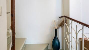 A staircase with a white railing and a dark blue vase with dried flowers on the landing.