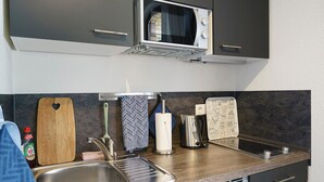 Eine Küche mit eingebauter Mikrowelle, Spüle aus Edelstahl und modernen Geräten.