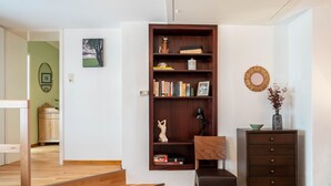 Quarto com estante de madeira, escrivaninha, cadeira, cômoda e cama.