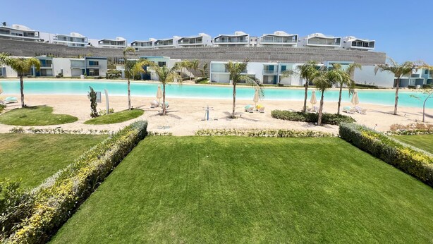 Et resort med swimmingpool, strand og moderne bygninger.