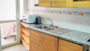 Une cuisine avec des meubles de rangement en bois, un four à micro-ondes, un évier et un crédence décorée.