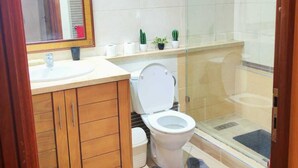 Une salle de bain avec un meuble-lavabo en bois, des toilettes, une douche en verre et un miroir.