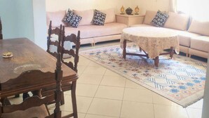 Un salon comprenant une table à manger en bois, un canapé, un tapis à motifs et un lustre.