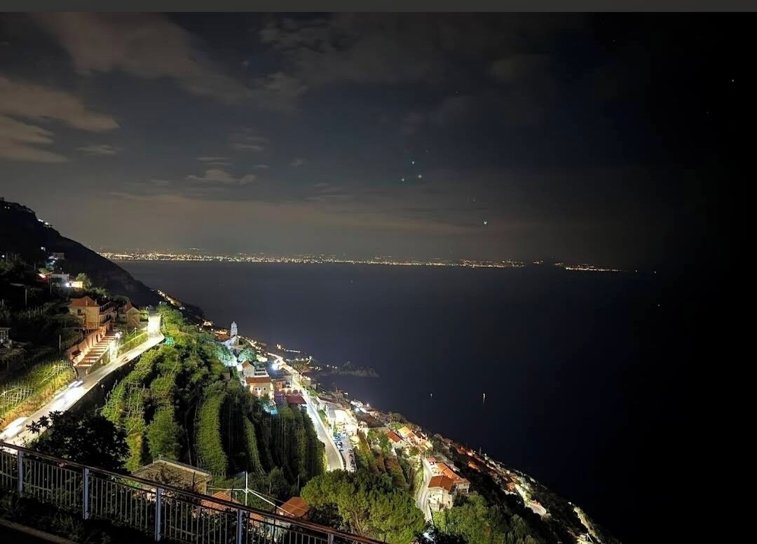 Una cittadina costiera di notte, con una strada che serpeggia tra case a schiera.