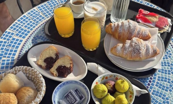 A breakfast tray with croissants, juice, and pastries on a blue-tiled table. - Al Chiar di Luna - Furore (Furore)