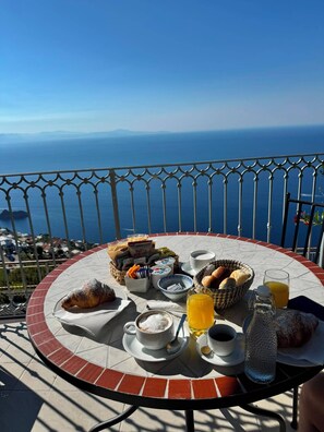 Ein Frühstückstisch auf einem Balkon mit herrlichem Blick auf Meer und Berge.