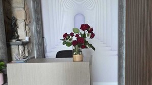 A reception desk with a vase of red roses, a stone wall, and a white arched doorway. - Al Chiar di Luna - Furore (Furore)
