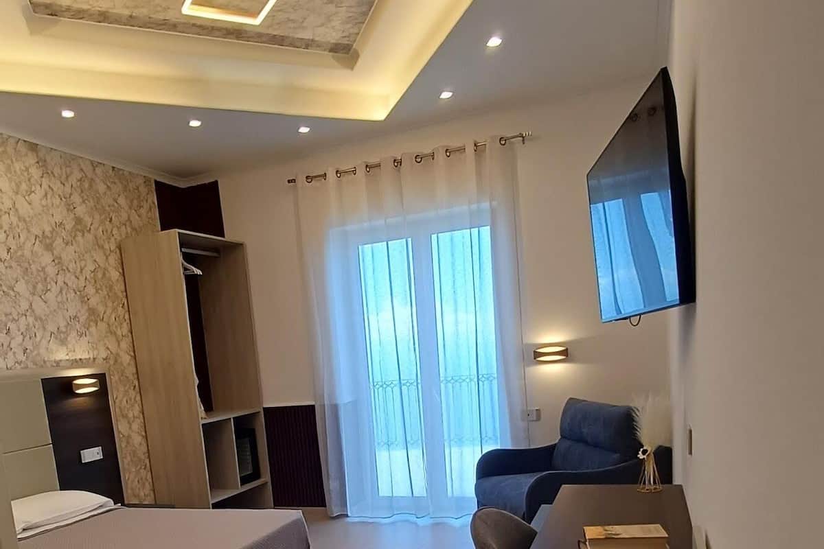 Un dormitorio moderno con cama, escritorio, silla y televisor montado en la pared.