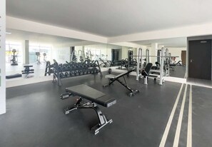 A modern gym with various exercise equipment, including dumbbells, benches, and weight machines.