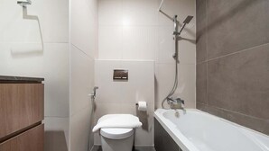 Een moderne badkamer met toilet, douchetoilet en bad.