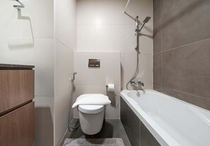 A modern bathroom with a toilet, bidet, and bathtub. - Studio w/ Pool & Gym at JVC Living Garden (Dubai)