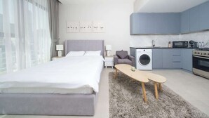 Een moderne hotelkamer met een groot bed, een wasmachine, een kitchenette en uitzicht op de stad.