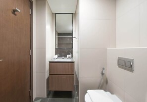 A modern bathroom with a wooden door, a sink with a mirror, and a toilet.