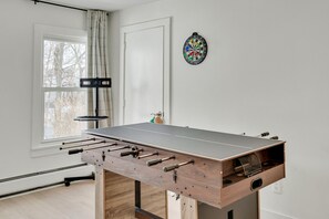 A foosball table in a room with a window, a dartboard, and a door. - Modern 3BR Apartment: 4 Bed, 2 Bath, 2 Floors, Games & BBQ (Cambridge)