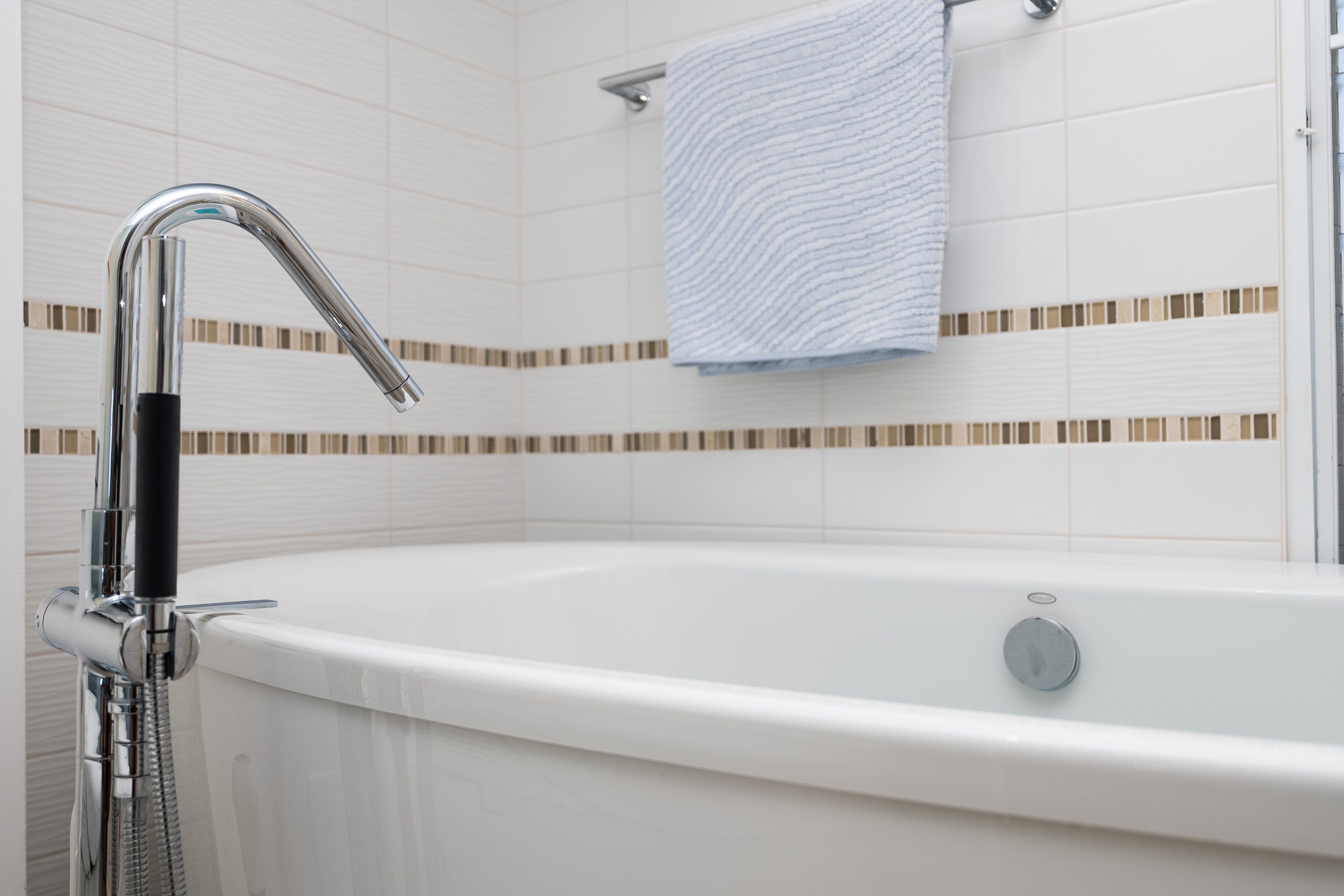 Un baño con bañera, ducha y una toalla colgada en la pared.
