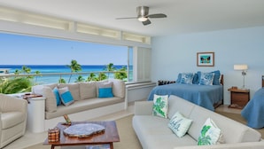 A hotel room with a balcony, a bed with blue bedding, a sofa, a coffee table, and a ceiling fan. - Oceanfront Gold Coast with Full Ocean & Diamond Head Views! Free Parking! (Honolulu)