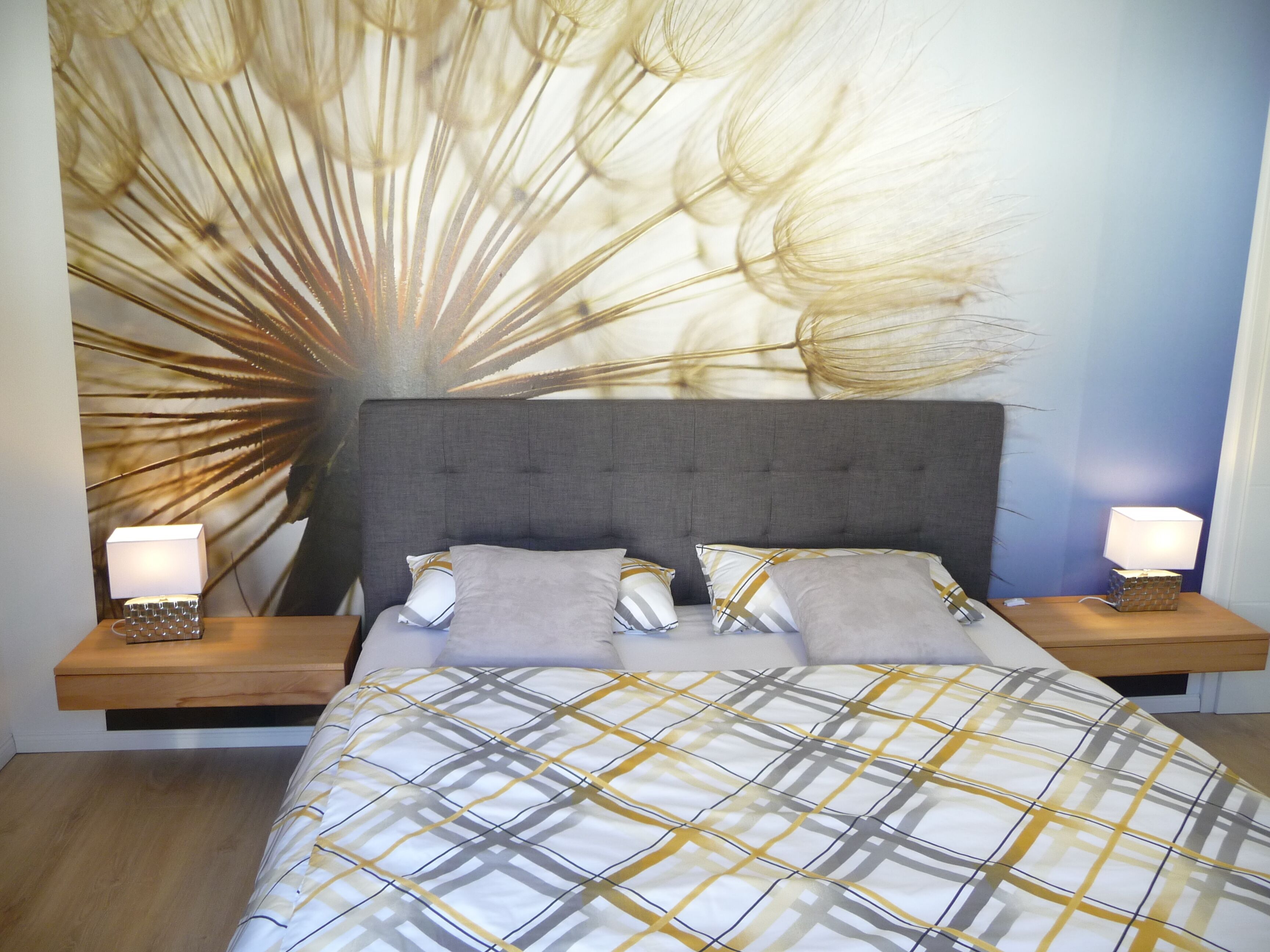 A bedroom with a large bed, two bedside tables, and a wall art piece.