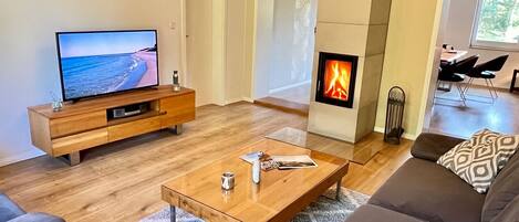 Ein modernes Wohnzimmer mit Fernseher, Kamin, Sofa und Couchtisch.