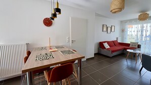 A modern living space with a dining table, chairs, a sofa, and a small side table. - House between forest and beach - 4 guests (Saint-Jean-de-Monts)