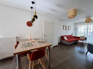 Ein zeitgemäßer Wohnraum mit Esstisch, Stühlen, einer Couch und einem kleinen Beistelltisch.
