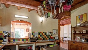 Een keuken met houten kastjes, een betegelde achterwand, hangend keukengerei en een koffieapparaat.
