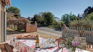Een terras met een eettafel, een fles wijn en een bloempot.