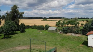 A rural landscape with fields, trees, and a small building.
