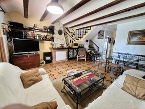 Ein gemütliches Wohnzimmer mit Kamin, Fernseher und einer Treppe, die in ein weiteres Geschoss führt.