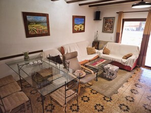 Ein Wohnzimmer mit einem Glastisch, einer Couch, einem gemusterten Teppich und Bildern an den Wänden.