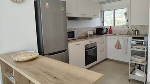 Eine moderne Küche mit einem Edelstahl-Kühlschrank, einer Mikrowelle, einem Backofen und einer Holz Arbeitsplatte.