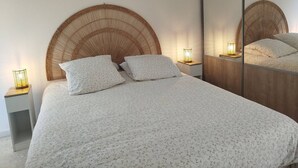 Ein Schlafzimmer mit einem großen Bett, zwei Nachttischen, einem Spiegel und einem an der Wand befestigten Kopfteil.