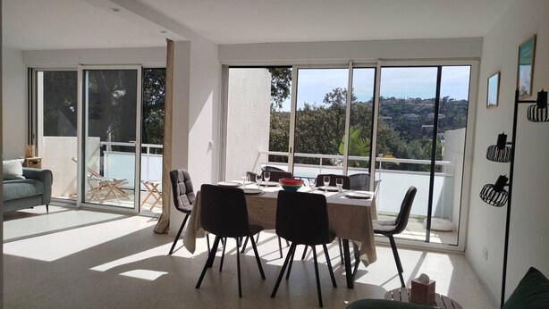Ein großzügiger Wohnbereich mit Balkon, einem Esstisch für vier Personen und einem grünen Sofa.