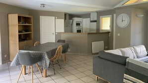 A compact living space with a dining table, chairs, a sofa, a kitchenette, and a clock on the wall. - Villa with pool, pets allowed - 6 guests (Moliets-et-Maa)