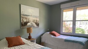 A room with two beds, a painting on the wall, a lamp, and a window with a view. - Villa with pool, pets allowed - 6 guests (Moliets-et-Maa)