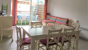 Un comedor con una mesa y sillas, un sofá y vistas a través de un ventanal.