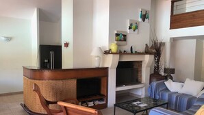 Ein Wohnzimmer mit Kamin, einer Couch, einem Couchtisch und einem Korbstuhl.