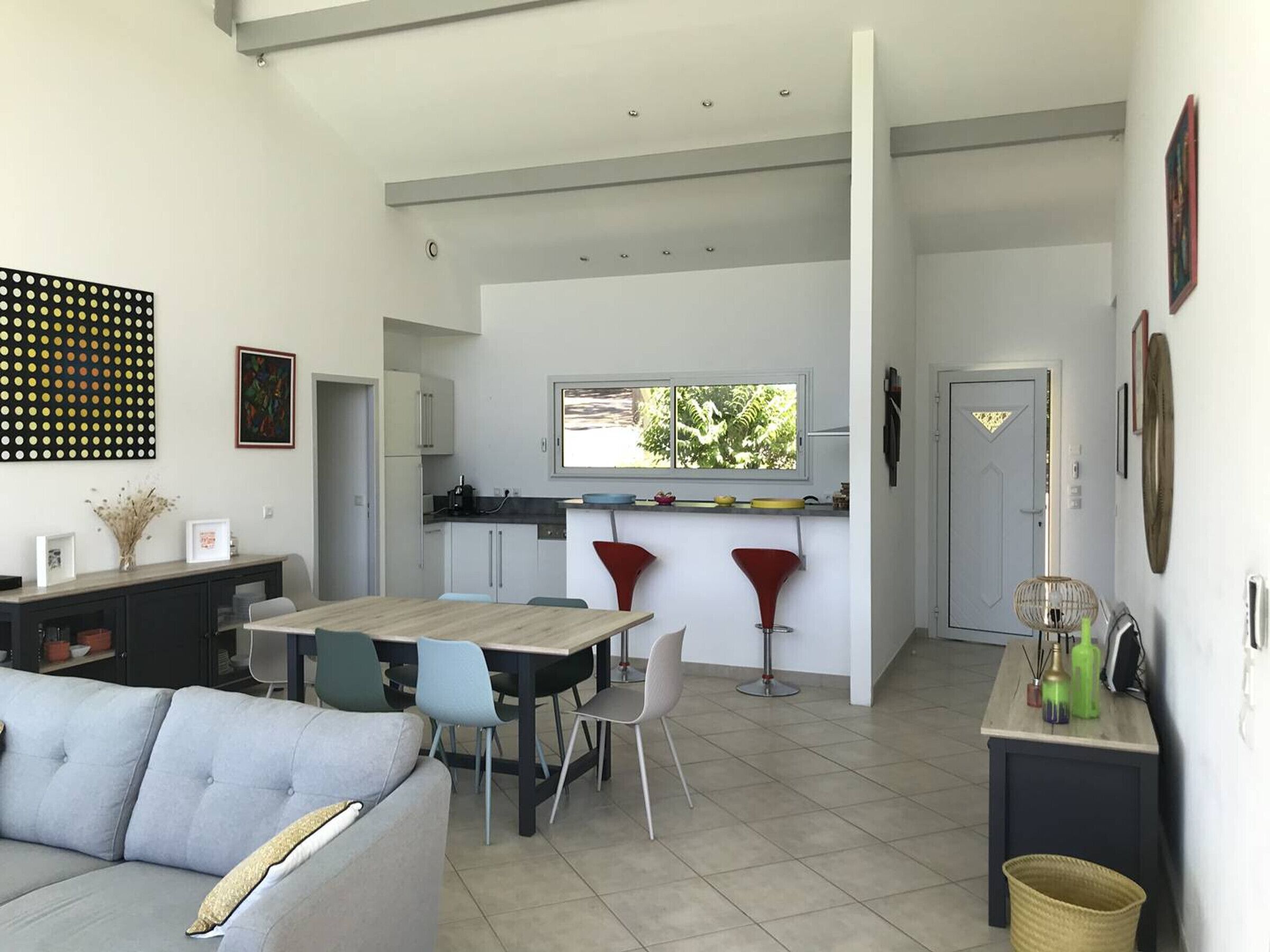 A modern kitchen with a dining area, a sofa, and a TV.