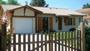 Ein eingeschossiges Haus mit Ziegeldach, Garage und Holzzaun.