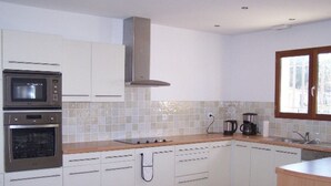 Eine moderne Küche mit weißen Schränken, einem eingebauten Backofen, einer Mikrowelle, einem Herd und einem Fenster.