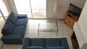 Ett vardagsrum med en soffa, ett soffbord, ett TV-bord och ett element.